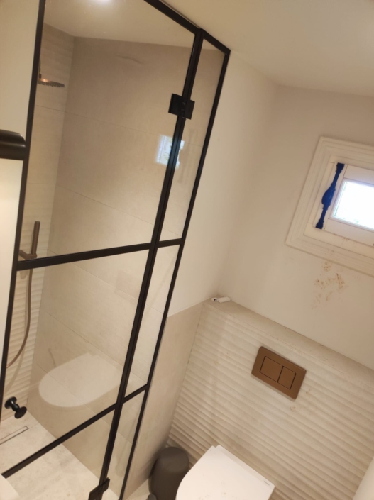 Installation de parois de douche en verre sur-mesure style atelier avec profils noirs dans un hôtel particulier à Nice.