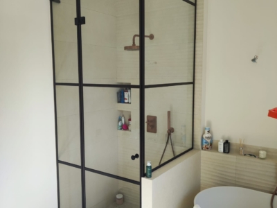 Installation de parois de douche en verre sur-mesure style atelier avec profils noirs dans un hôtel particulier à Nice.