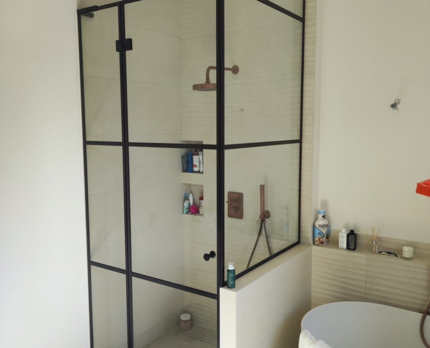 Installation de parois de douche en verre sur-mesure style atelier avec profils noirs dans un hôtel particulier à Nice.