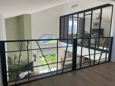 Vue d'ensemble d'une verrière et garde-corps en verre sur-mesure en mezzanine.