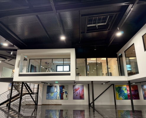 Installation de deux escaliers en acier et bois avec garde-corps en verre transparent dans un showroom automobile à Aix-en-Provence.
