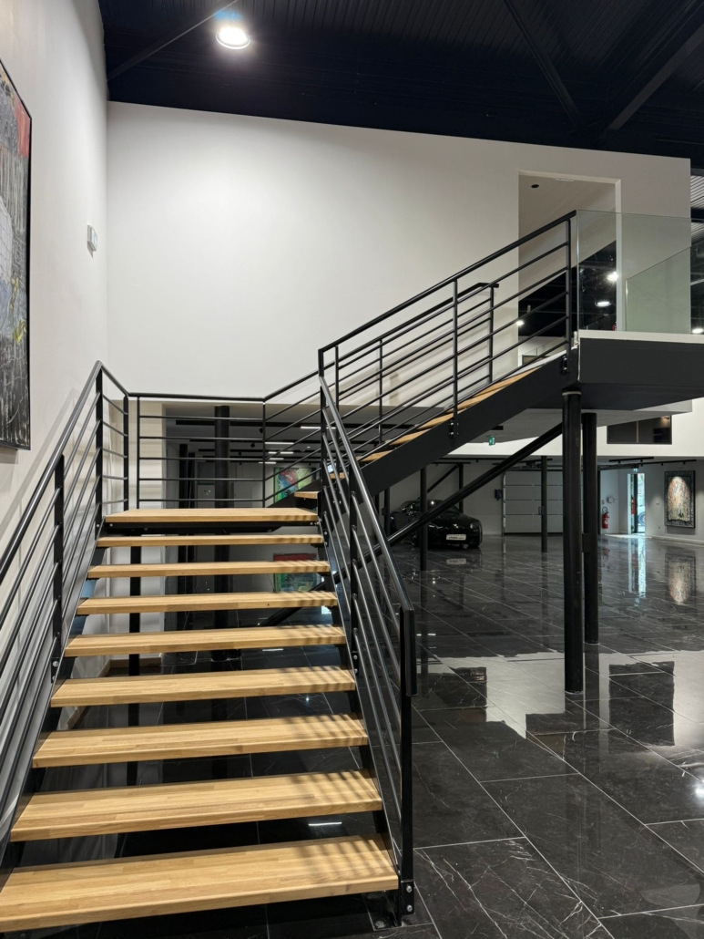 Installation de deux escaliers en acier et bois avec garde-corps en verre transparent dans un showroom automobile à Aix-en-Provence.